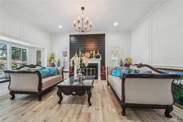 living room featuring ornamental molding, an inviting chandelier, and light hardwood / wood-style floors