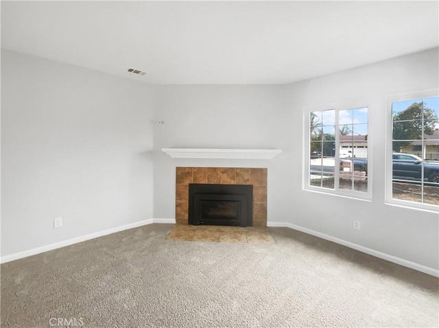 unfurnished living room featuring light carpet, a fireplace, visible vents, and baseboards