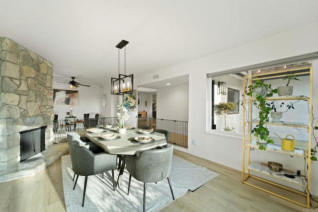 dining room featuring a stone fireplace and light hardwood / wood-style floors