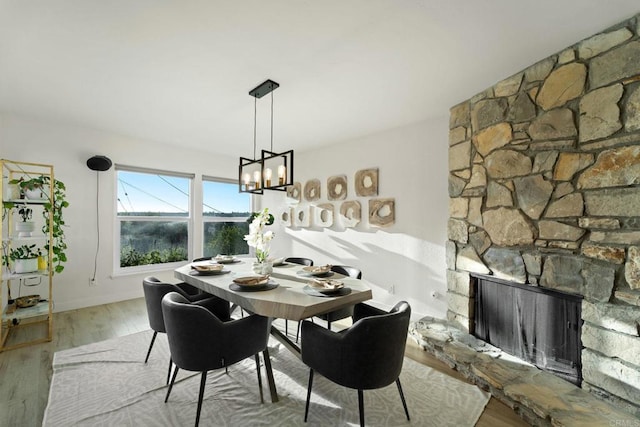 dining space featuring a fireplace, a chandelier, and light hardwood / wood-style flooring