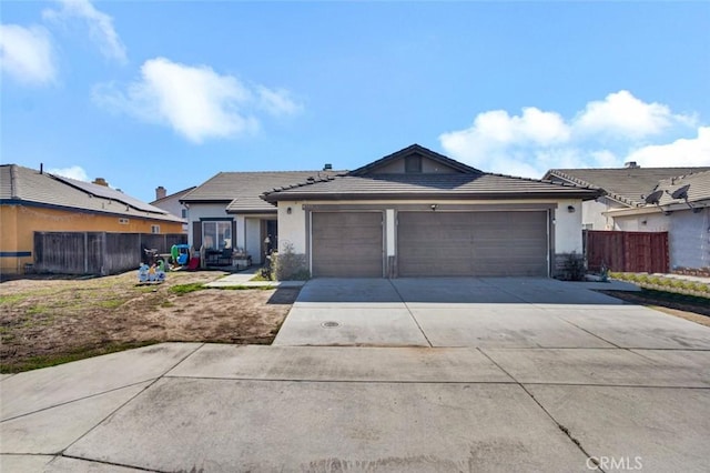 view of front of house featuring an attached garage, fence, concrete driveway, and stucco siding