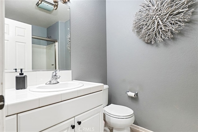 full bathroom featuring baseboards, a textured wall, toilet, an enclosed shower, and vanity