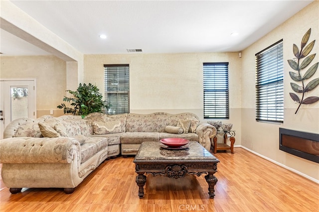 living room with light wood finished floors, visible vents, and baseboards