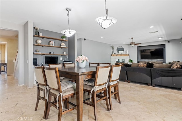 dining room featuring ceiling fan, a glass covered fireplace, visible vents, and recessed lighting