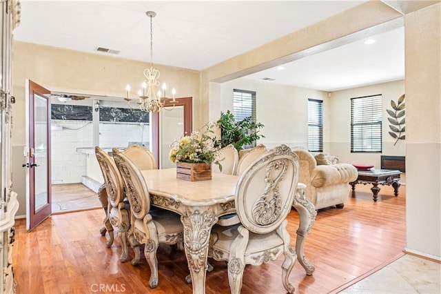 dining area with light wood-style flooring, visible vents, and an inviting chandelier