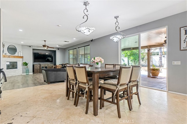 dining space with a wealth of natural light, a glass covered fireplace, baseboards, and recessed lighting