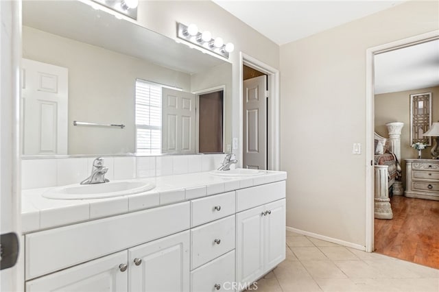 full bathroom featuring double vanity, tile patterned flooring, baseboards, and a sink