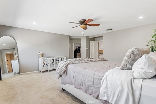 carpeted bedroom featuring arched walkways, recessed lighting, visible vents, a ceiling fan, and a walk in closet