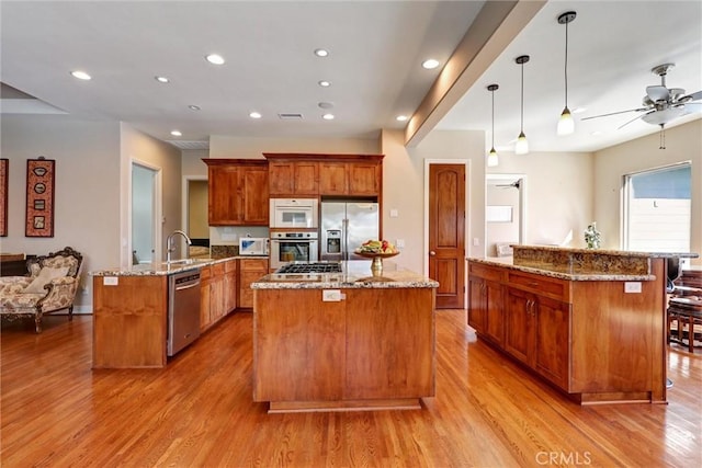 kitchen featuring pendant lighting, a large island, ceiling fan, stainless steel appliances, and kitchen peninsula