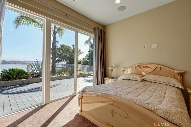 bedroom featuring a water view, carpet flooring, and access to outside