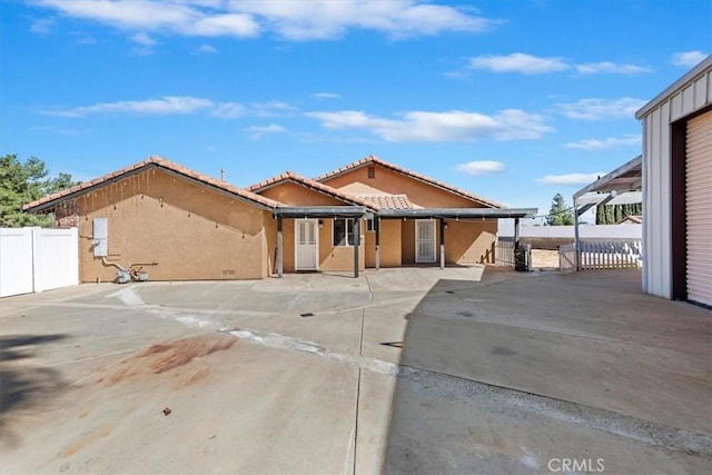 view of front of property featuring a tiled roof, a patio area, fence, and stucco siding