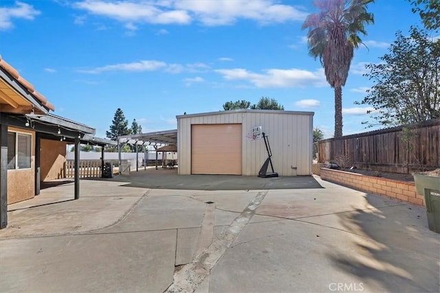 view of outdoor structure with fence, concrete driveway, and an outdoor structure