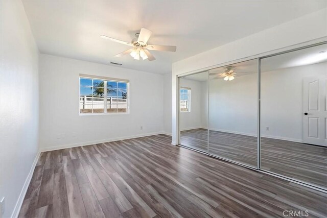 unfurnished bedroom with dark wood-style floors, multiple windows, and baseboards