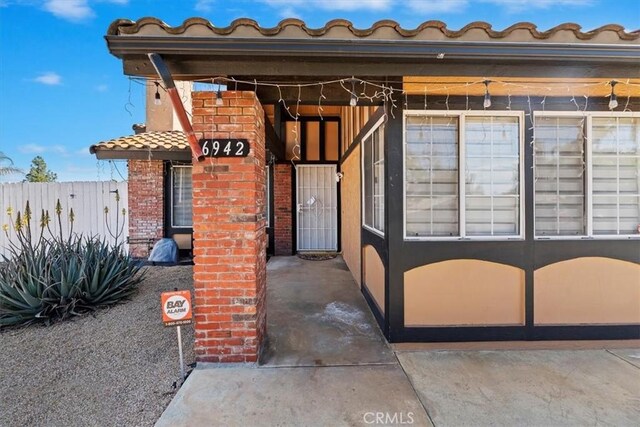 exterior space with a tile roof, brick siding, fence, and stucco siding