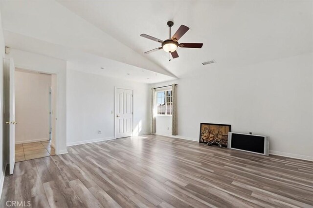 unfurnished living room featuring baseboards, visible vents, a ceiling fan, lofted ceiling, and light wood-type flooring