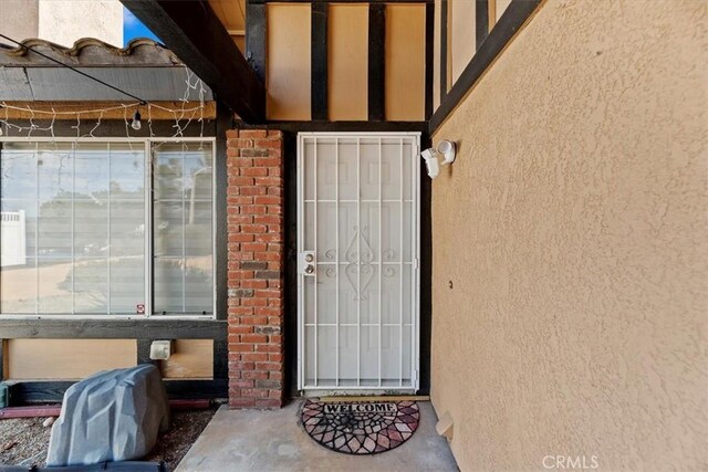 doorway to property featuring stucco siding and brick siding