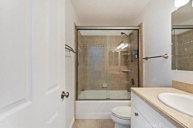 bathroom with toilet, tile patterned floors, bath / shower combo with glass door, and vanity