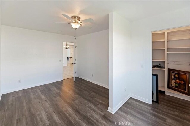 interior space featuring dark wood-style floors, baseboards, and ceiling fan with notable chandelier