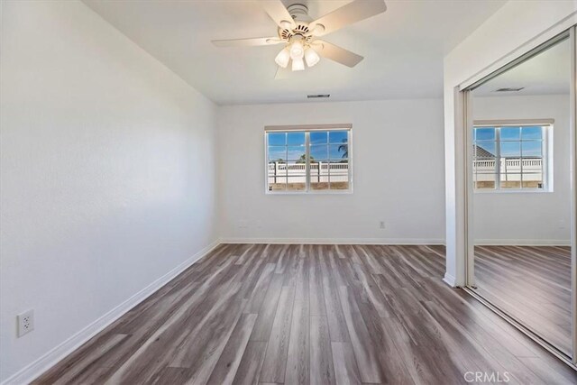 unfurnished bedroom featuring visible vents, wood finished floors, a ceiling fan, and baseboards