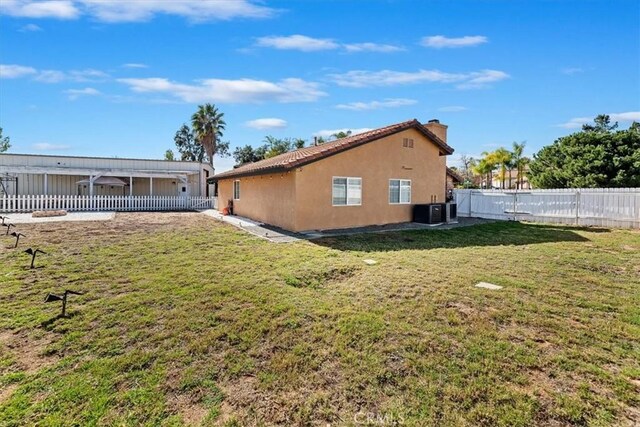 back of house with cooling unit, a fenced backyard, a yard, and stucco siding