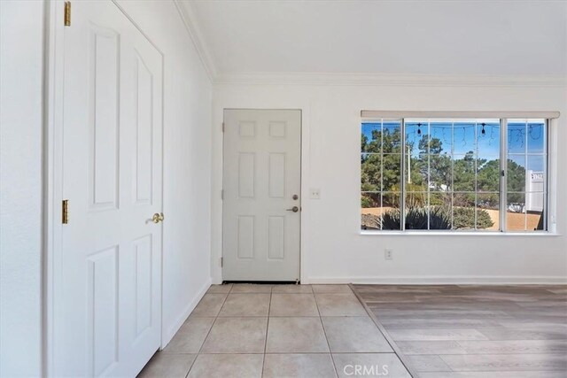 foyer featuring light tile patterned floors, baseboards, and ornamental molding