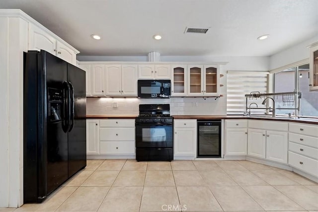 kitchen featuring wine cooler, visible vents, glass insert cabinets, a sink, and black appliances