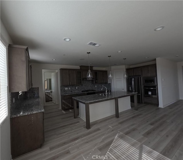 kitchen featuring wall oven, black fridge with ice dispenser, sink, dark stone counters, and stainless steel microwave