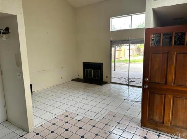 unfurnished living room with a towering ceiling and light tile patterned floors