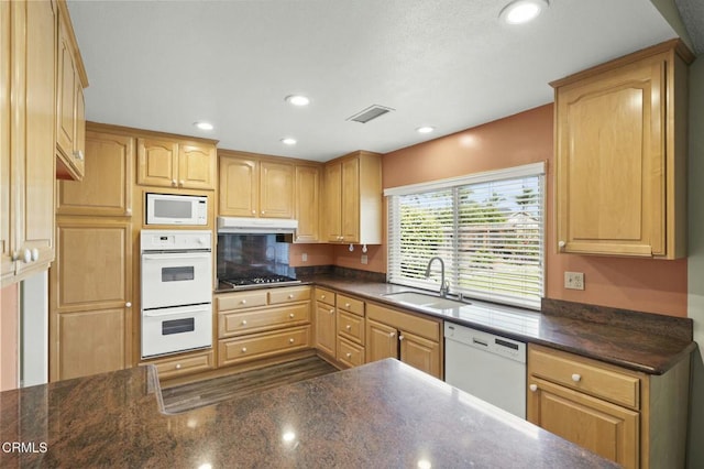 kitchen with under cabinet range hood, light brown cabinetry, recessed lighting, white appliances, and a sink