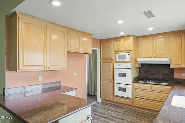 kitchen featuring visible vents, under cabinet range hood, light brown cabinetry, wood finished floors, and white appliances