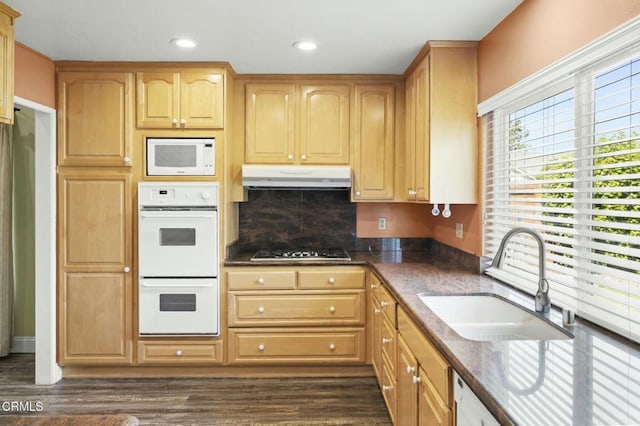 kitchen featuring under cabinet range hood, a sink, dark wood finished floors, recessed lighting, and white appliances