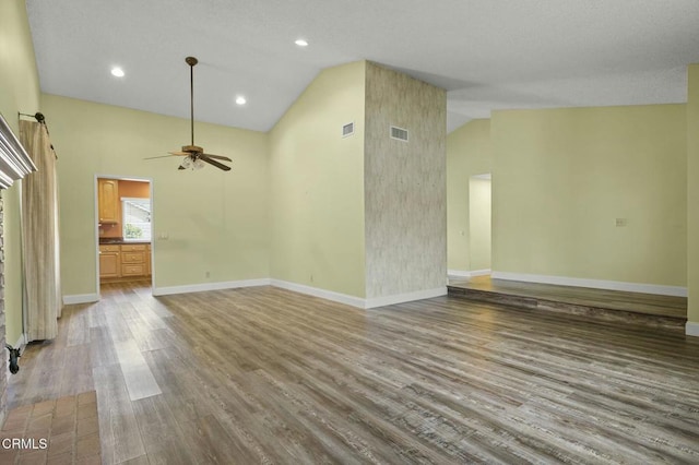 spare room featuring visible vents, high vaulted ceiling, baseboards, and wood finished floors