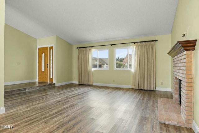 unfurnished living room with baseboards, lofted ceiling, wood finished floors, and a fireplace