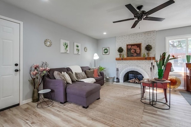 living room featuring light hardwood / wood-style flooring, ceiling fan, and a fireplace