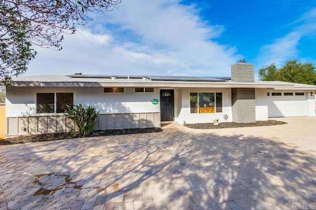 single story home featuring solar panels and a garage