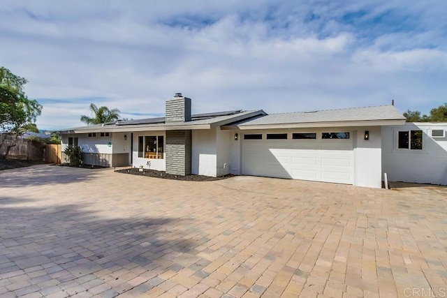 ranch-style house featuring a garage and solar panels