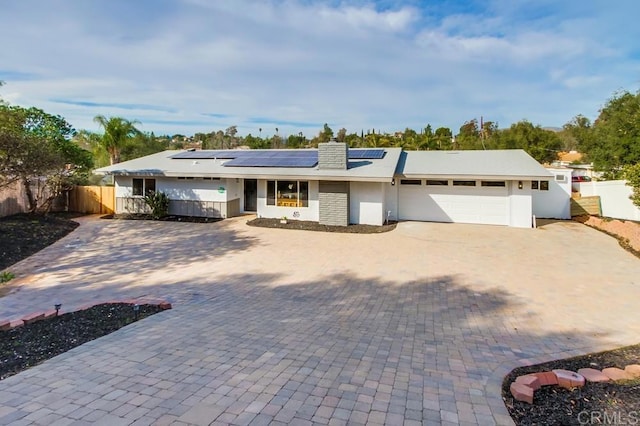 ranch-style home with a garage and solar panels