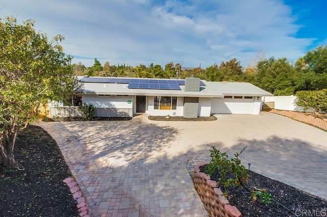 single story home featuring a garage and solar panels