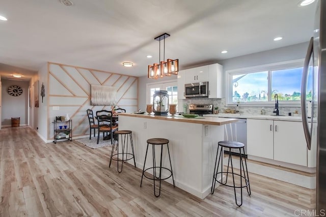 kitchen with white cabinetry, stainless steel appliances, a breakfast bar, and pendant lighting