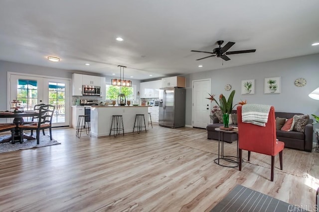 living room featuring light wood-type flooring, french doors, and ceiling fan