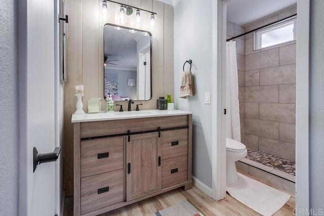 bathroom featuring toilet, ceiling fan, curtained shower, hardwood / wood-style floors, and vanity