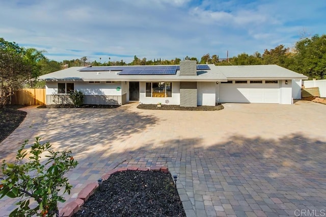 single story home featuring solar panels and a garage