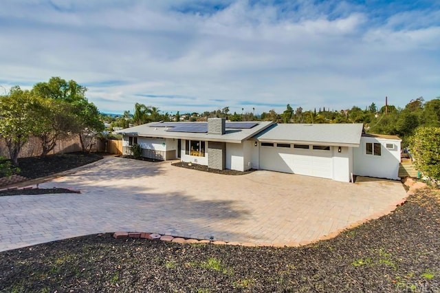 ranch-style home featuring a garage and solar panels