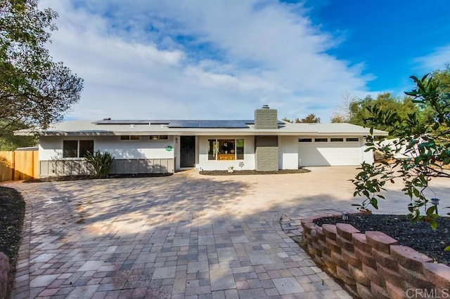 ranch-style house with solar panels and a garage