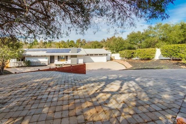 ranch-style home featuring a garage and solar panels