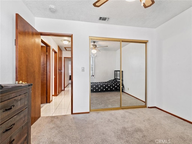 carpeted bedroom with a textured ceiling, a closet, and ceiling fan