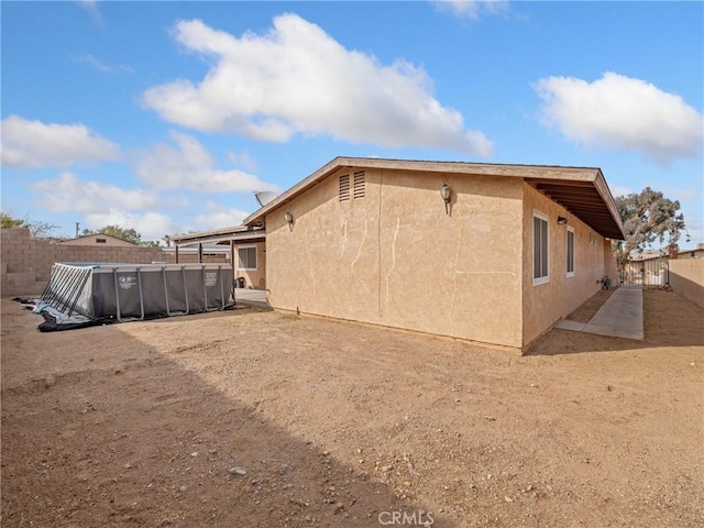 rear view of property featuring a fenced in pool