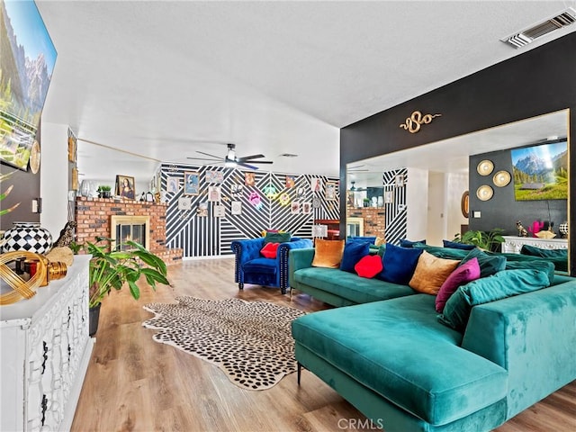 living room featuring a fireplace, light hardwood / wood-style flooring, and ceiling fan