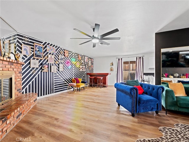 living room featuring hardwood / wood-style flooring, ceiling fan, bar area, and a fireplace