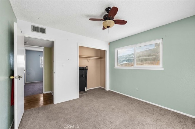 unfurnished bedroom featuring a textured ceiling, light carpet, ceiling fan, and a closet